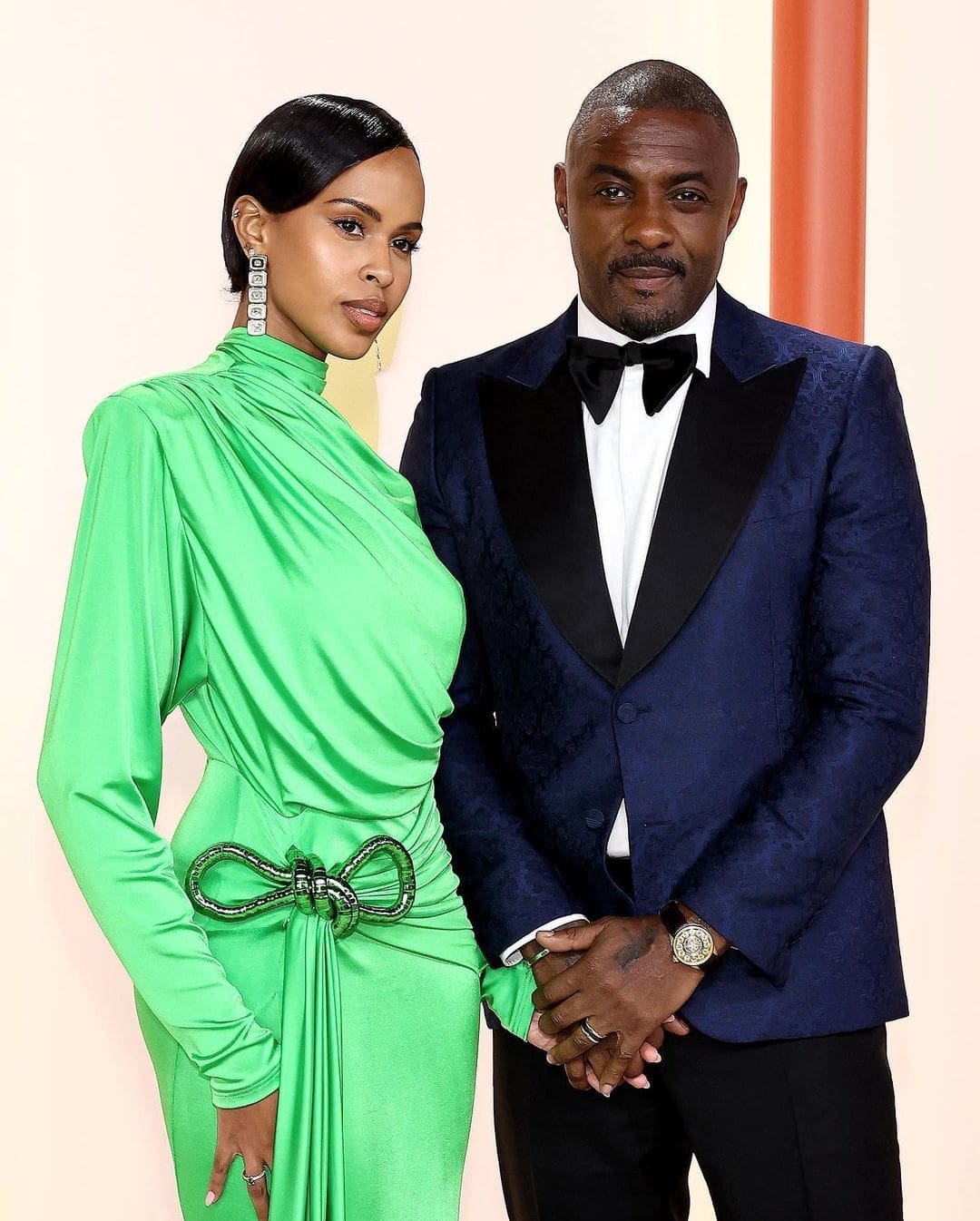 Idris Elba wearing Gucci's G-Timeless Planetarium while posing beside his wife, Sabrina Dhowre Elba