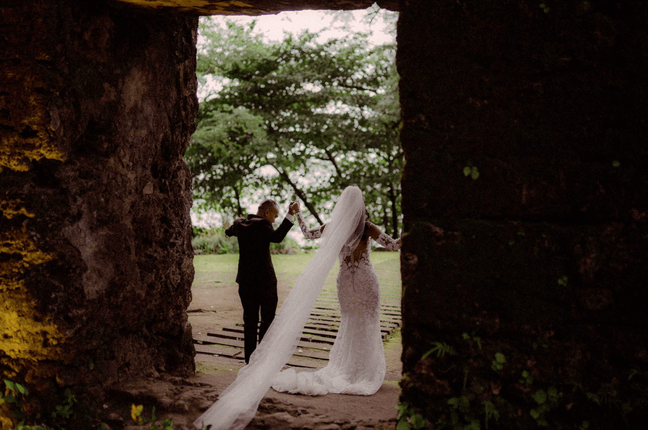 The happy couple hold hands in a picturesque and lush backdrop